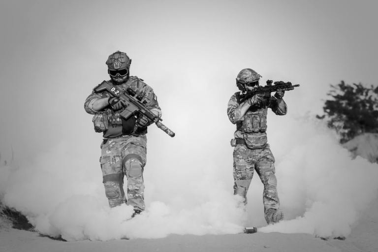 two men in military clothing with guns